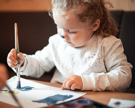 Mädchen malt ein Bild mit Pinsel und Farbe