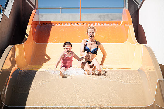 Mother and child on wide water slide