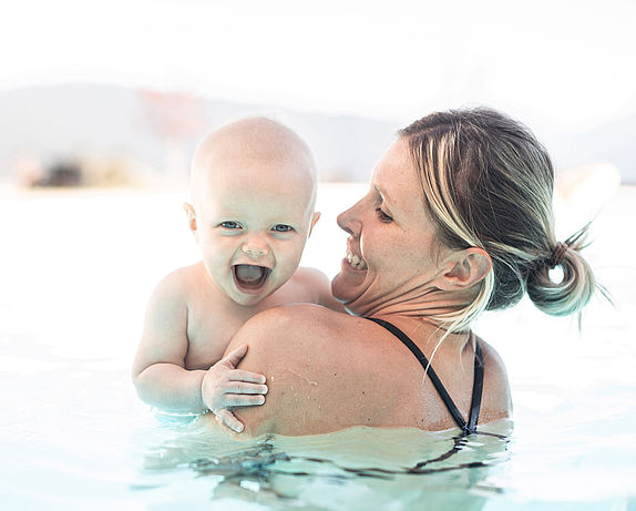 Mutter hält Baby auf dem Arm im Schwimmbad