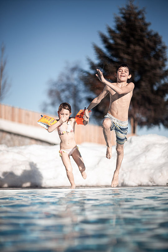 Two children jump into the swimming pool