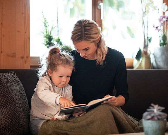 Mother reads a book to daughter