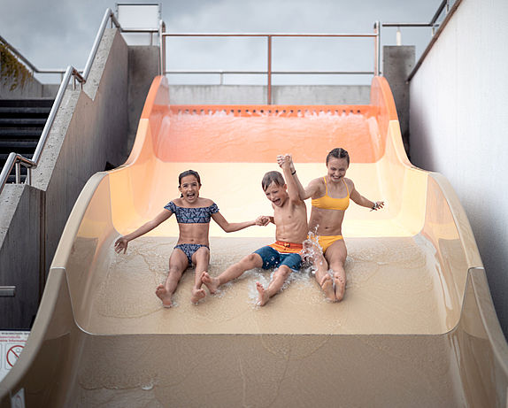 Tre bambini su un ampio scivolo d'acqua