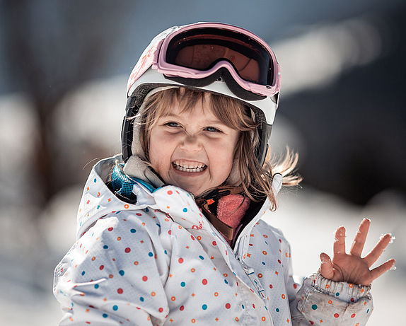 Little girl in ski gear waves