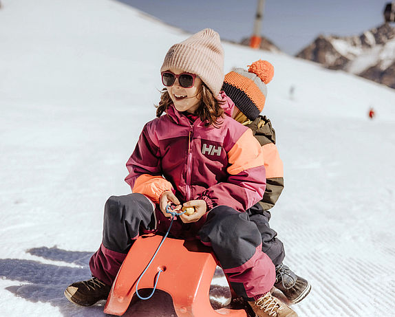 Due bambini in slitta su una pista di neve