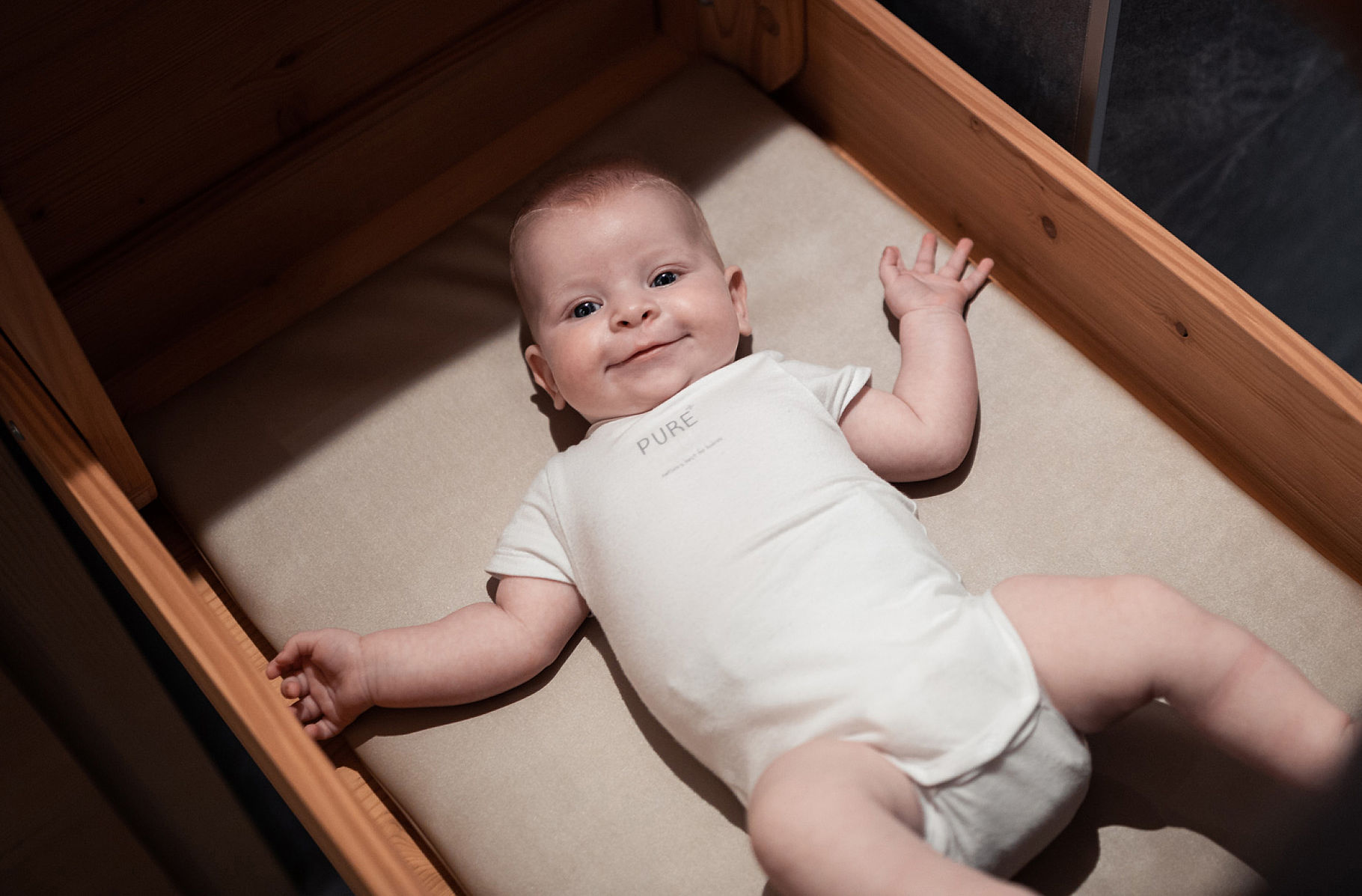 Baby with white bodysuit in the cradle